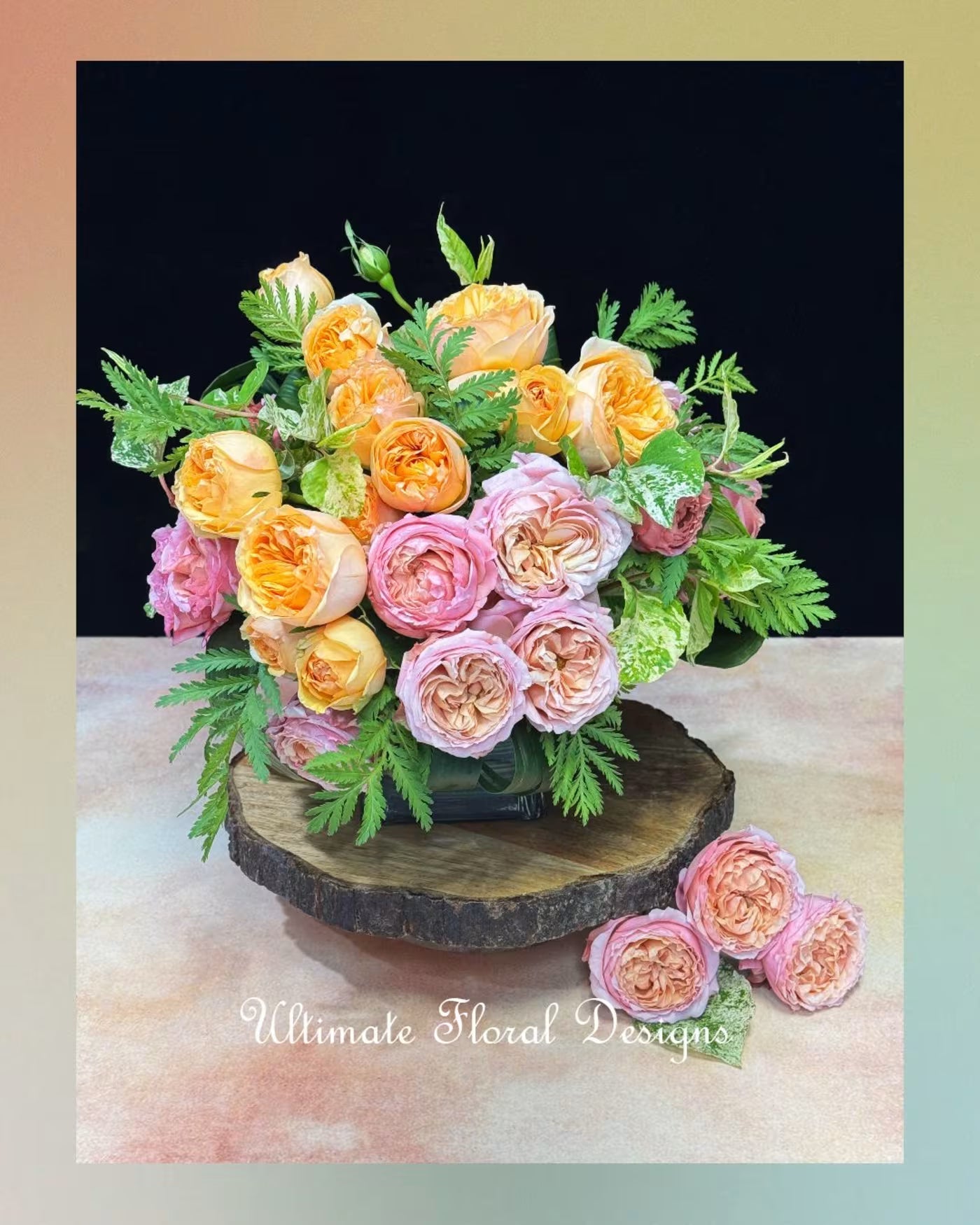 Garden spray roses, pink and peach on a clear vase with 'Ultimate Floral Designs' branding.