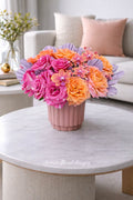 Coral and pink garden roses with mini orange orchids in a blush ceramic vase — luxury flower delivery by Ultimate Floral Designs
